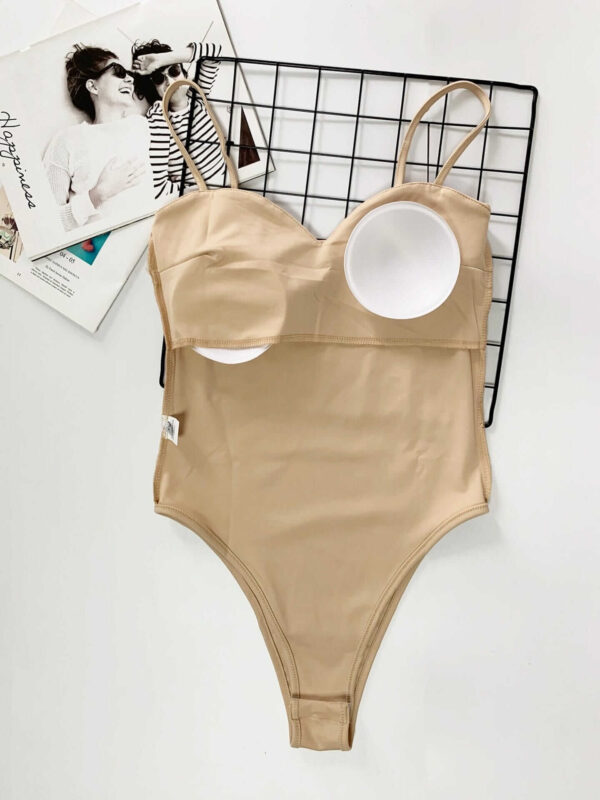 A beige Solid Color Bodysuit with Spaghetti Straps on top of a magazine.