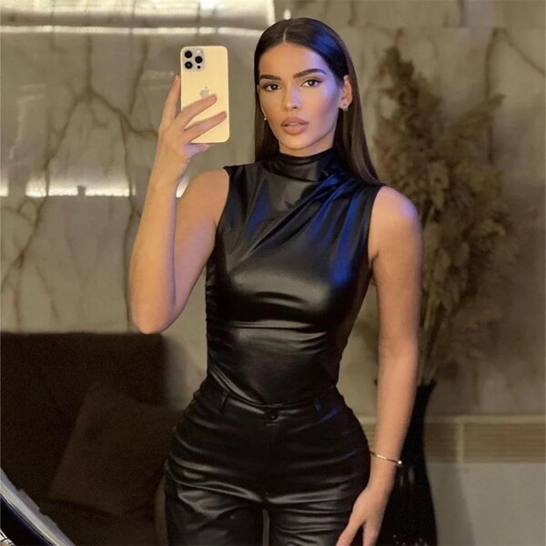 Woman taking a mirror selfie in a Vegan Leather Tank Top and black outfit.