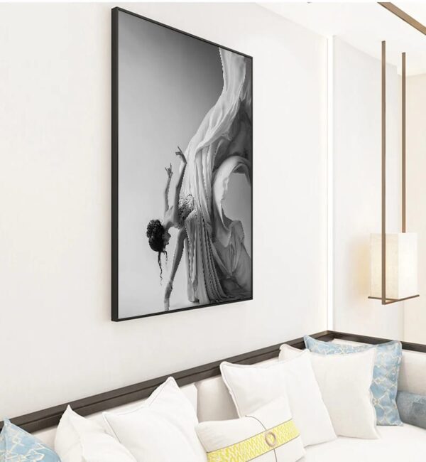 A black and white framed artwork of a dancer in motion, displaying Grace, displayed on a living room wall above a sofa with decorative pillows.