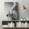 An artistic monochrome painting of a woman draped in flowing fabric with Grace on a wall above a shelf with white books and green plants.