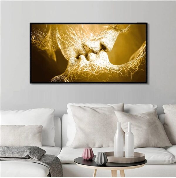 A framed LOVE KISS art piece with gold and black tones, symbolizing a love kiss, hanging above a sofa with white cushions in a modern living room.