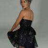 Woman in a SEQUIN BOW CORSET DRESS posing with her back to the camera looking over her shoulder.