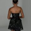 Woman in a sequin bow corset dress standing with her back to the camera.