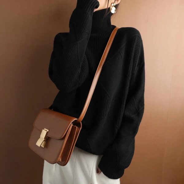 Woman in a black LOOSE CASHMERE SWEATER with a brown shoulder bag.