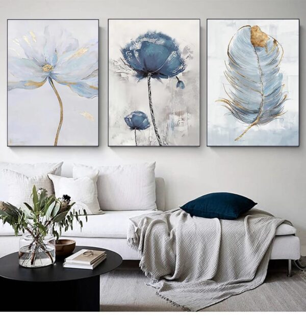A serene living room featuring a white sofa with a throw blanket and blue pillows, complemented by a triptych of SCANDINAVIAN FLOWER wall art.