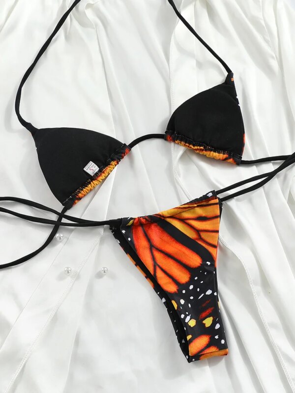 A BUTTERFLY GIRL TWO PIECE SWIMSUIT featuring a black and orange butterfly pattern lies flat on a white fabric background.