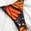 Close-up of a BUTTERFLY GIRL TWO PIECE SWIMSUIT bottom with orange and black patterns on a white fabric background.