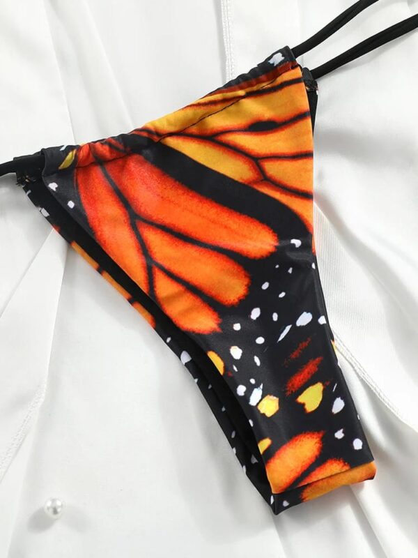 Close-up of a BUTTERFLY GIRL TWO PIECE SWIMSUIT bottom with orange and black patterns on a white fabric background.