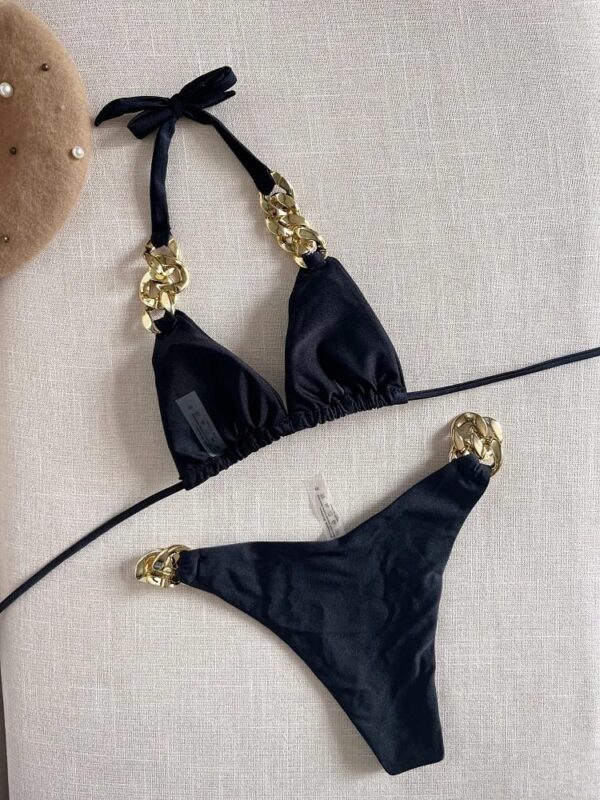 A black TWO PIECE BRAZILIAN BIKINI SET with gold chain accents on the straps is displayed on a light fabric background.