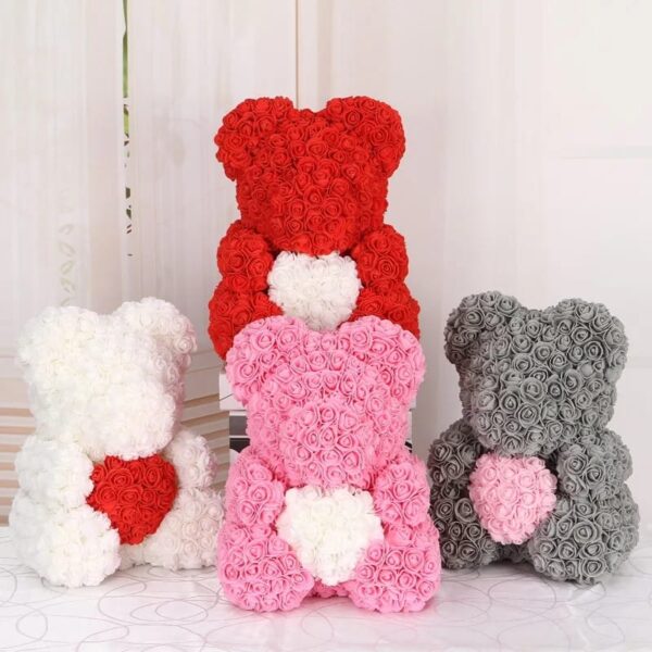 Four Teddy Bears of Roses—in white, red, pink, and gray—are arranged in a semi-circle. Each Teddy Bear of Roses features a heart shape on its chest or back.