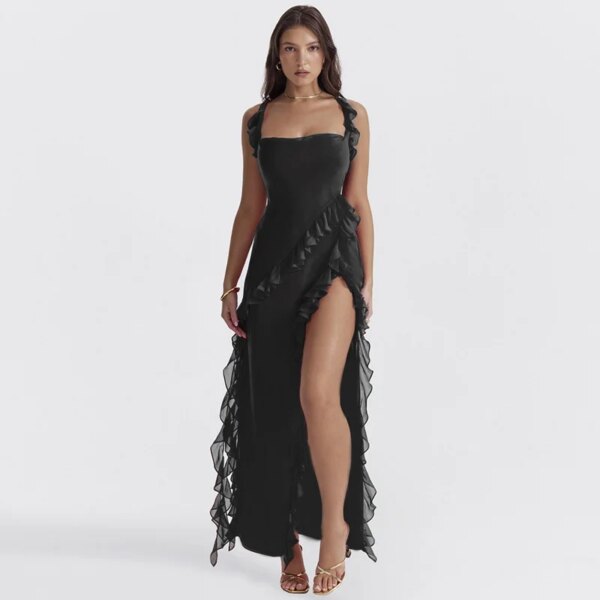 A woman in the Ruffles Trim Square Neck Slit Maxi Dress stands on a white background. The black, sleeveless dress features a square neck and ruffles trim that accentuates the elegance of its thigh-high slit design. She is wearing sandals and has her hands at her sides.